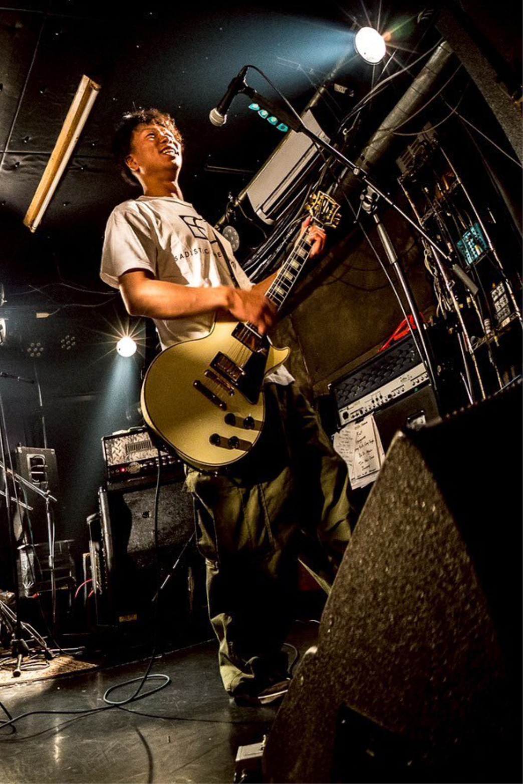 ライブハウスのステージでギターを演奏する、運営者の楽しげで情熱的な姿。音楽活動を通じて培った感性と表現力を象徴する自己紹介用写真。