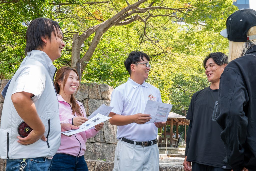 屋外で資料を持ちながら会話するBELLE HOMEスタッフの業務イメージ写真